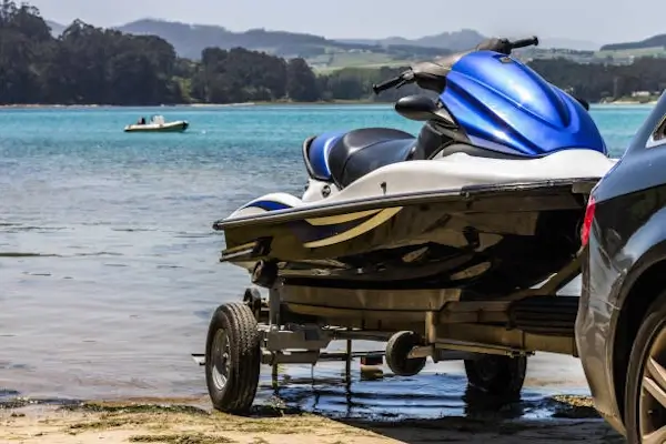Car towing a jet ski trailer toward the water, showing Smarter Towing’s technology for seamless and stress-free watersport transport.