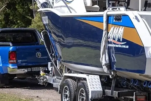 Pickup truck towing a large boat on a trailer, showing Smarter Towing’s reliable towing technology for safe and confident travel to the water.