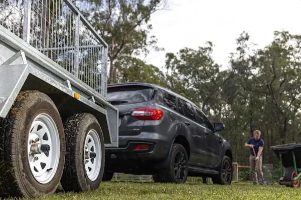 Car towing a rental trailer on grass, representing Smarter Towing’s reliable trailer monitoring for rental and commercial use